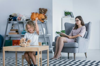 A child with behavioral problems sitting by a table and hitting