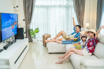 Family Traveller watching TV screen, pretending they on beach during summer in house.