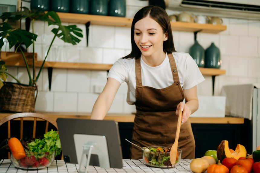 Young woman video blogger cooking at the kitchen and filming healthy food concept at home